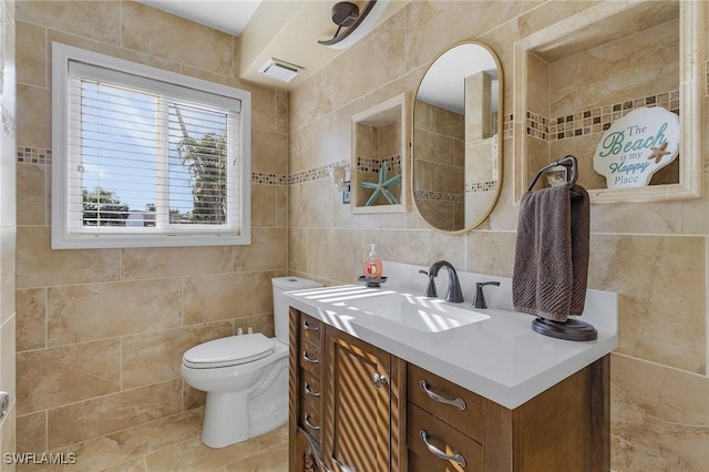 bathroom with vanity, toilet, and tile walls