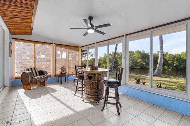 sunroom featuring a water view, ceiling fan, and vaulted ceiling