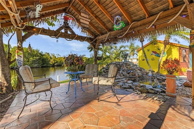 view of patio with a gazebo, a water view, and an outbuilding