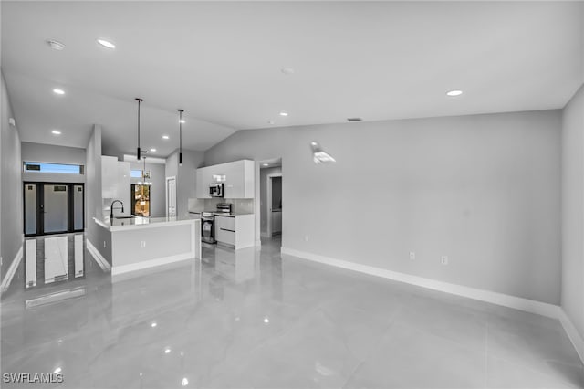 kitchen featuring appliances with stainless steel finishes, white cabinetry, a center island with sink, decorative light fixtures, and vaulted ceiling