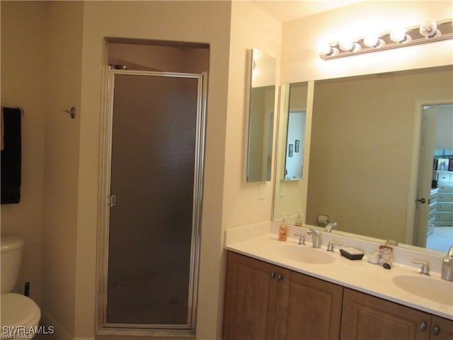 bathroom with vanity, toilet, and a shower with door