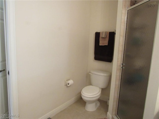 bathroom featuring tile patterned flooring, a shower with shower door, and toilet