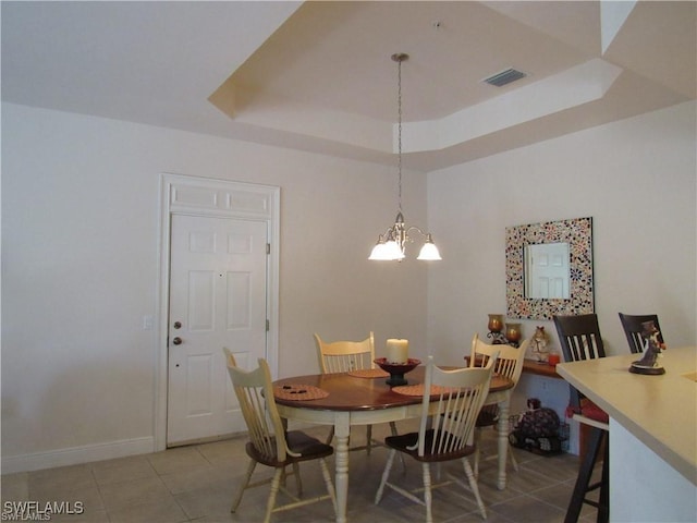 tiled dining room with a raised ceiling and a notable chandelier