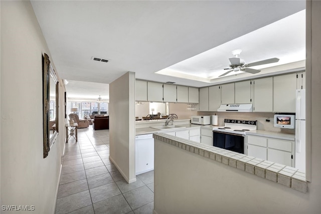 kitchen featuring sink, white appliances, tile counters, kitchen peninsula, and ceiling fan