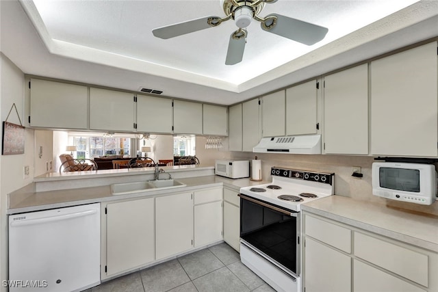 kitchen featuring sink, light tile patterned floors, white appliances, and a tray ceiling