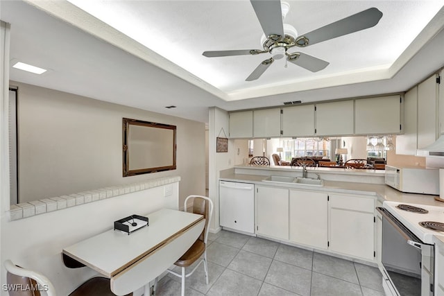 kitchen featuring white appliances, a raised ceiling, sink, and kitchen peninsula