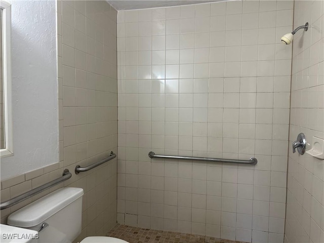 bathroom featuring tiled shower and toilet