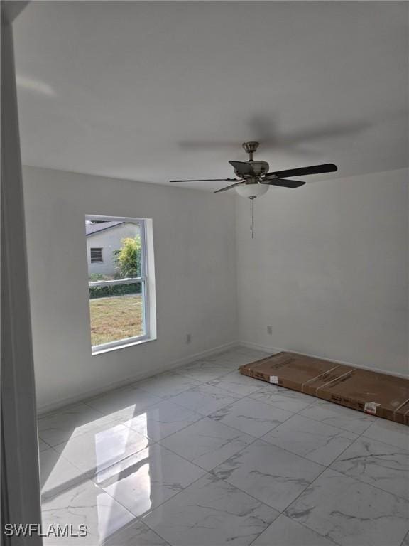 unfurnished room featuring marble finish floor and a ceiling fan