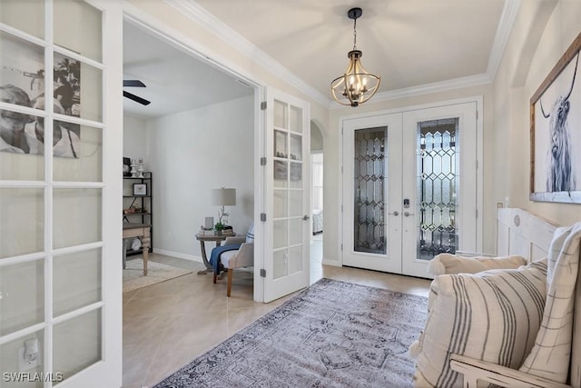 tiled foyer featuring crown molding, ceiling fan with notable chandelier, and french doors