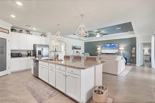 kitchen with appliances with stainless steel finishes, a kitchen island with sink, sink, and white cabinets