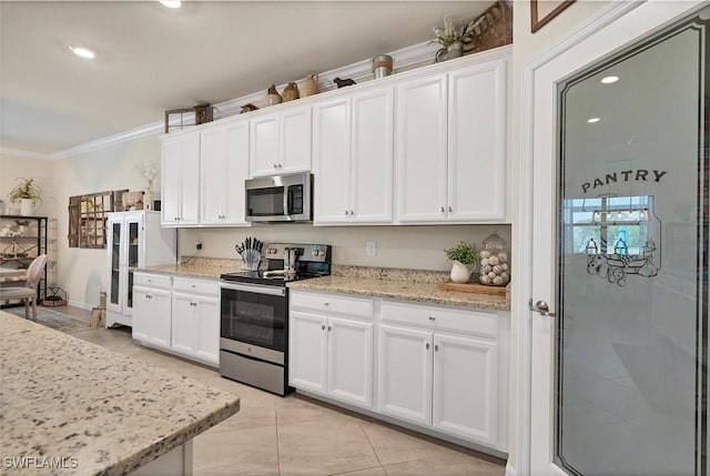 kitchen featuring white cabinetry, light stone counters, crown molding, and appliances with stainless steel finishes