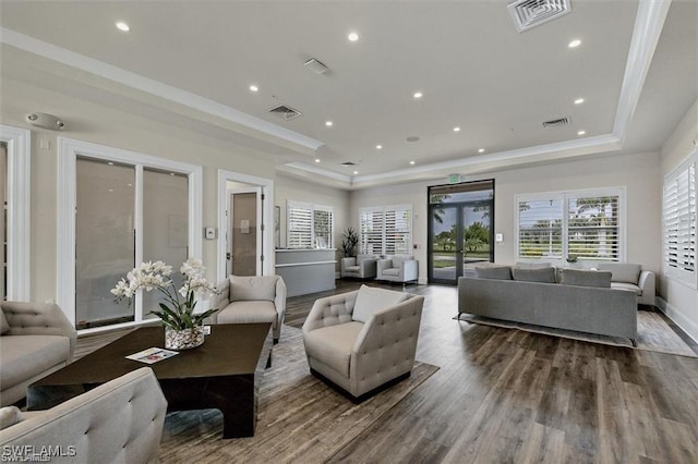 living room featuring ornamental molding, hardwood / wood-style floors, and a tray ceiling