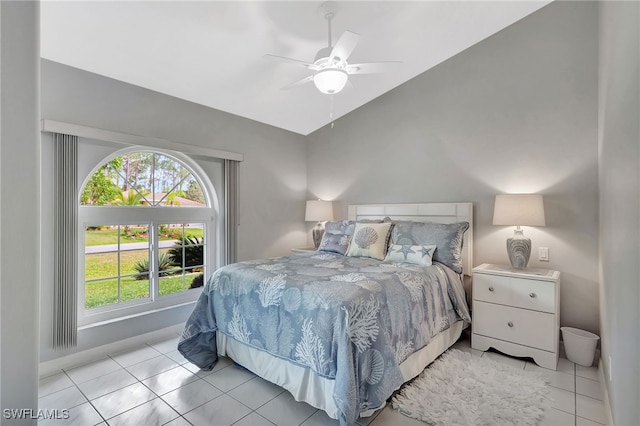 bedroom with a ceiling fan, vaulted ceiling, baseboards, and light tile patterned floors