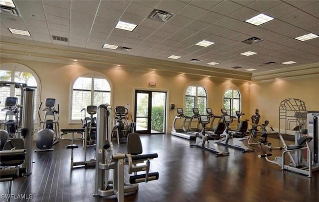 exercise room featuring crown molding, a towering ceiling, and a drop ceiling