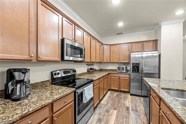 kitchen with crown molding, stainless steel appliances, light stone countertops, and light hardwood / wood-style floors