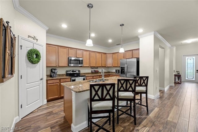 kitchen featuring sink, a breakfast bar, appliances with stainless steel finishes, light stone countertops, and an island with sink