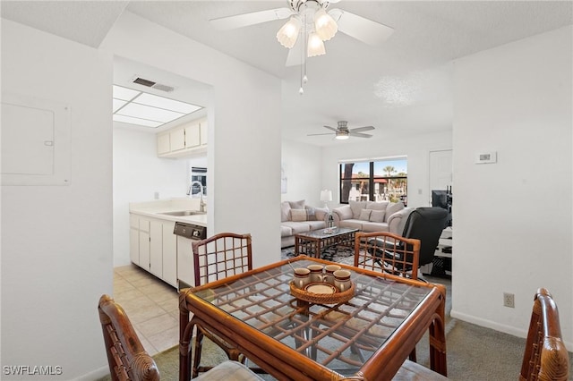 dining space featuring ceiling fan, sink, and light carpet