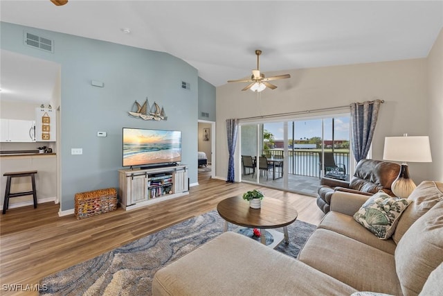 living area with lofted ceiling, visible vents, light wood-style floors, a ceiling fan, and baseboards