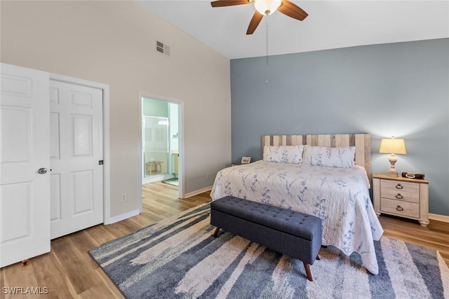 bedroom with ensuite bath, baseboards, visible vents, and wood finished floors