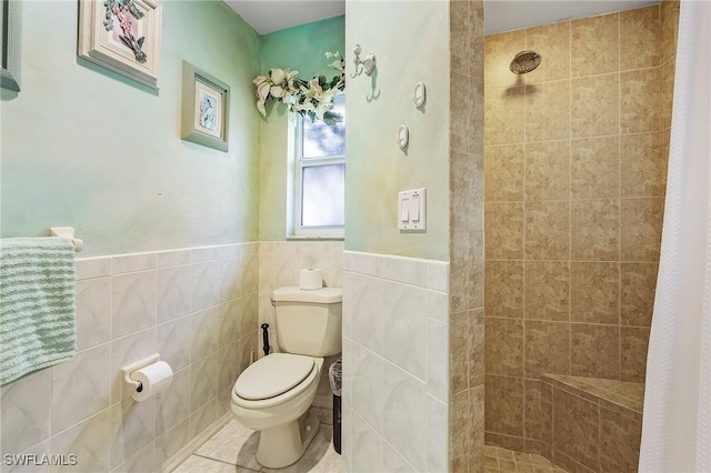 bathroom featuring a shower with curtain, toilet, tile patterned flooring, and tile walls