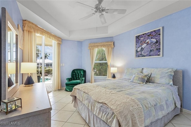 bedroom featuring multiple windows, access to exterior, a tray ceiling, and light tile patterned flooring