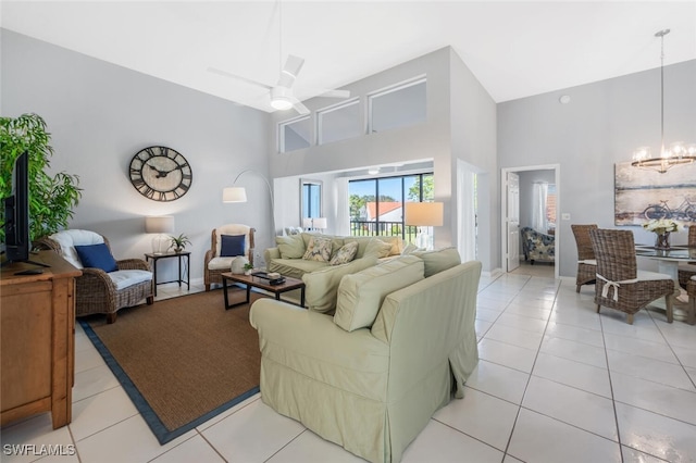 living room featuring ceiling fan with notable chandelier, a high ceiling, and light tile patterned flooring