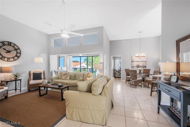 tiled living room with a towering ceiling and ceiling fan with notable chandelier