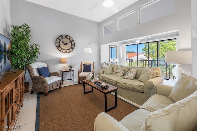 living room with a high ceiling, ceiling fan, and light tile patterned flooring