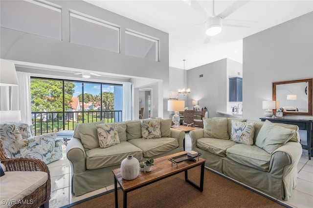 tiled living room with a towering ceiling and ceiling fan with notable chandelier