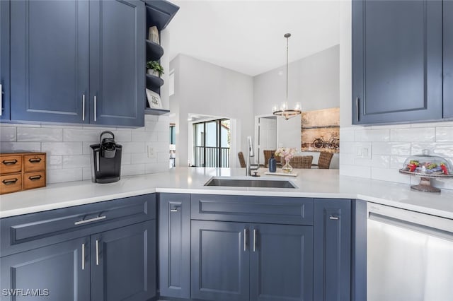 kitchen featuring sink, dishwashing machine, blue cabinetry, and decorative light fixtures