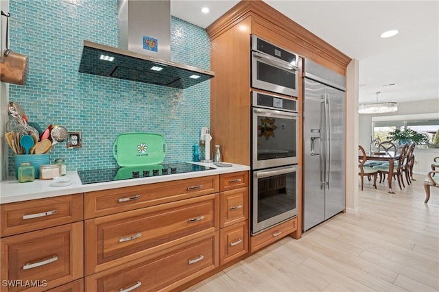 291 Flamingo St, Fort Myers Beach, FL 33931 - kitchen featuring light countertops, backsplash, appliances with stainless steel finishes, brown cabinets, and wall chimney range hood