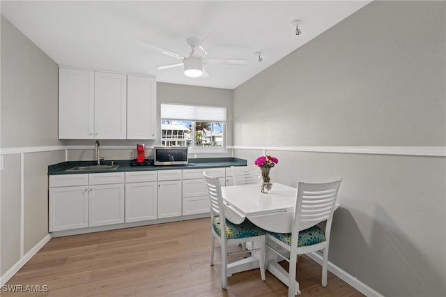 291 Flamingo St, Fort Myers Beach, FL 33931 - kitchen with stainless steel microwave, dark countertops, white cabinetry, a sink, and light wood-type flooring