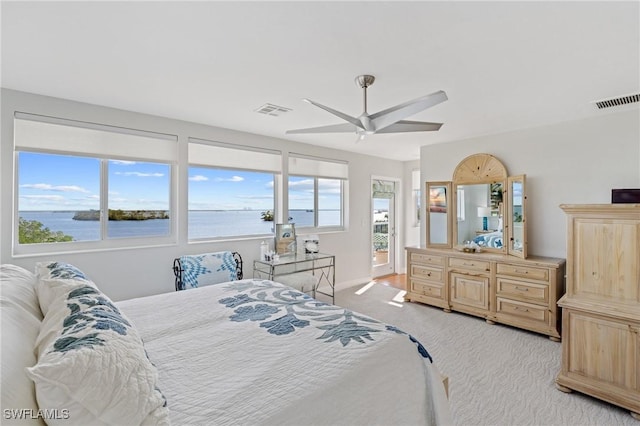 bedroom with light carpet, access to outside, ceiling fan, and a water view