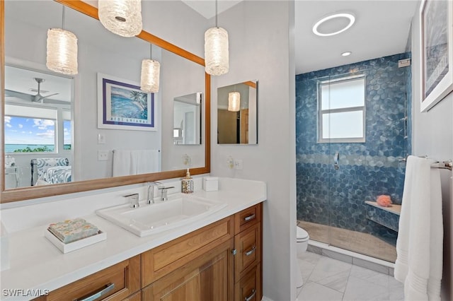 bathroom featuring ceiling fan, vanity, toilet, and a shower with shower door