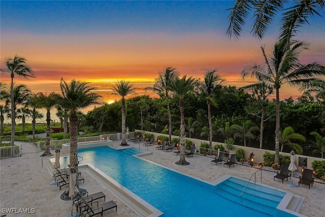 pool at dusk featuring a patio area