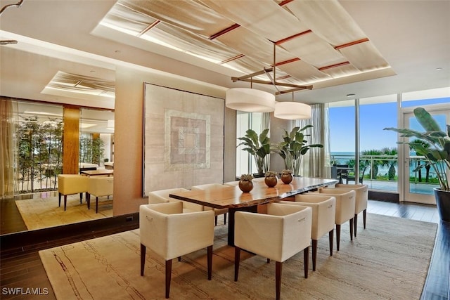 dining room featuring wood-type flooring, expansive windows, and a raised ceiling