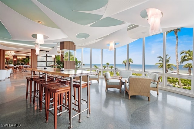 dining room with floor to ceiling windows, a beach view, and a water view