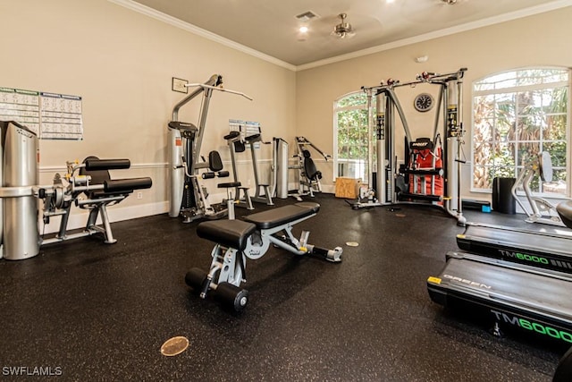 exercise room with baseboards, visible vents, and crown molding