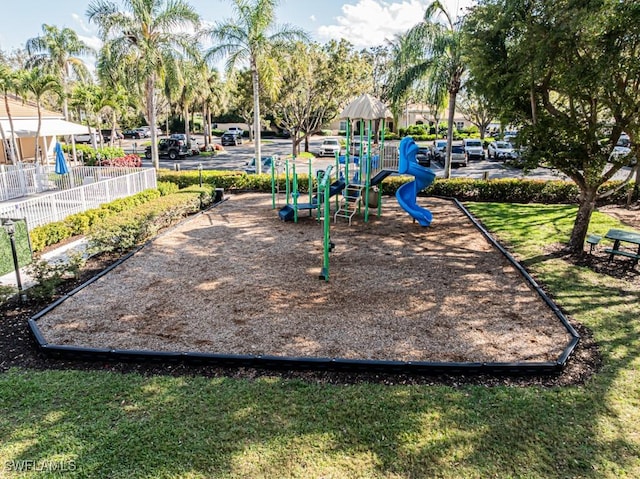 community jungle gym with a lawn and fence