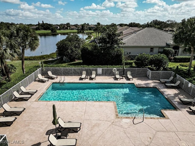 pool with a water view, fence, and a patio