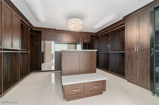 walk in closet with an inviting chandelier and light tile patterned floors