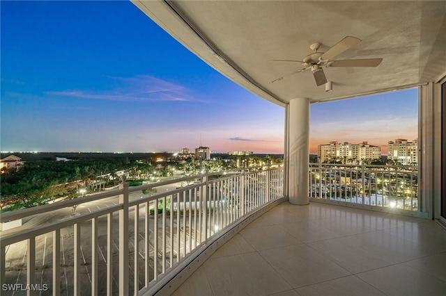 balcony at dusk featuring ceiling fan and a view of city