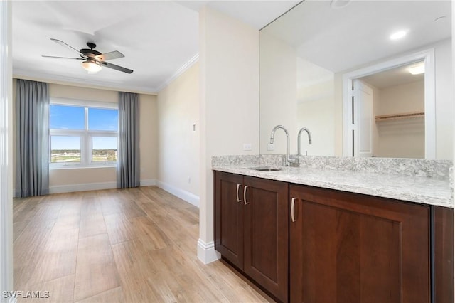 interior space with ceiling fan, light wood-style flooring, a sink, baseboards, and ornamental molding