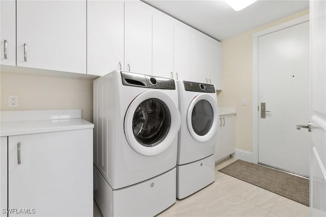 laundry area featuring cabinet space, light tile patterned floors, and washing machine and clothes dryer