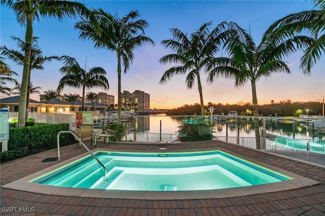 pool at dusk with a water view and fence