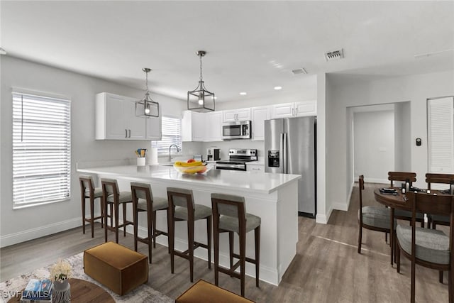 779 108th Ave N, Naples, FL 34108 - kitchen with decorative light fixtures, a breakfast bar area, white cabinets, kitchen peninsula, and stainless steel appliances