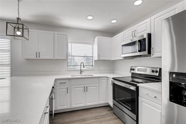 779 108th Ave N, Naples, FL 34108 - kitchen featuring sink, dark wood-type flooring, appliances with stainless steel finishes, white cabinetry, and decorative light fixtures