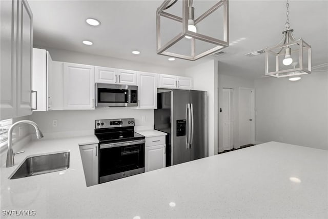 kitchen with white cabinetry, appliances with stainless steel finishes, decorative light fixtures, and sink