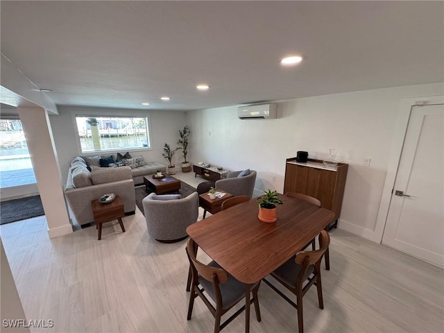 dining area featuring a wall mounted air conditioner and light hardwood / wood-style flooring