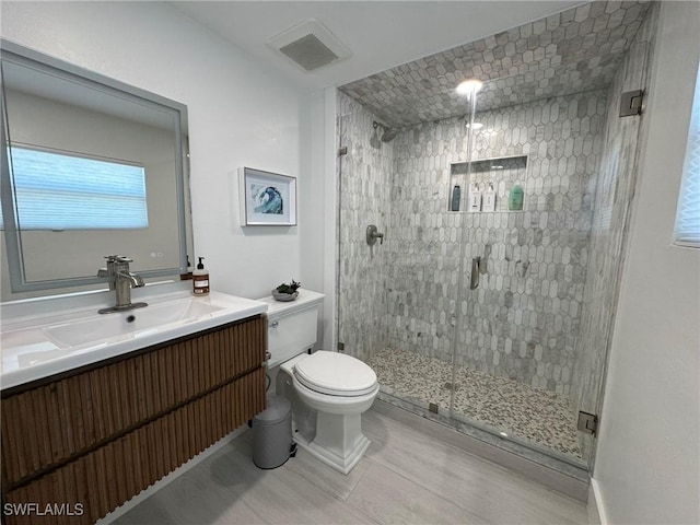 bathroom featuring vanity, toilet, and a shower with shower door